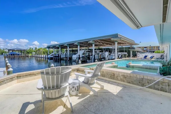a view of a swimming pool with couches chairs in front of house