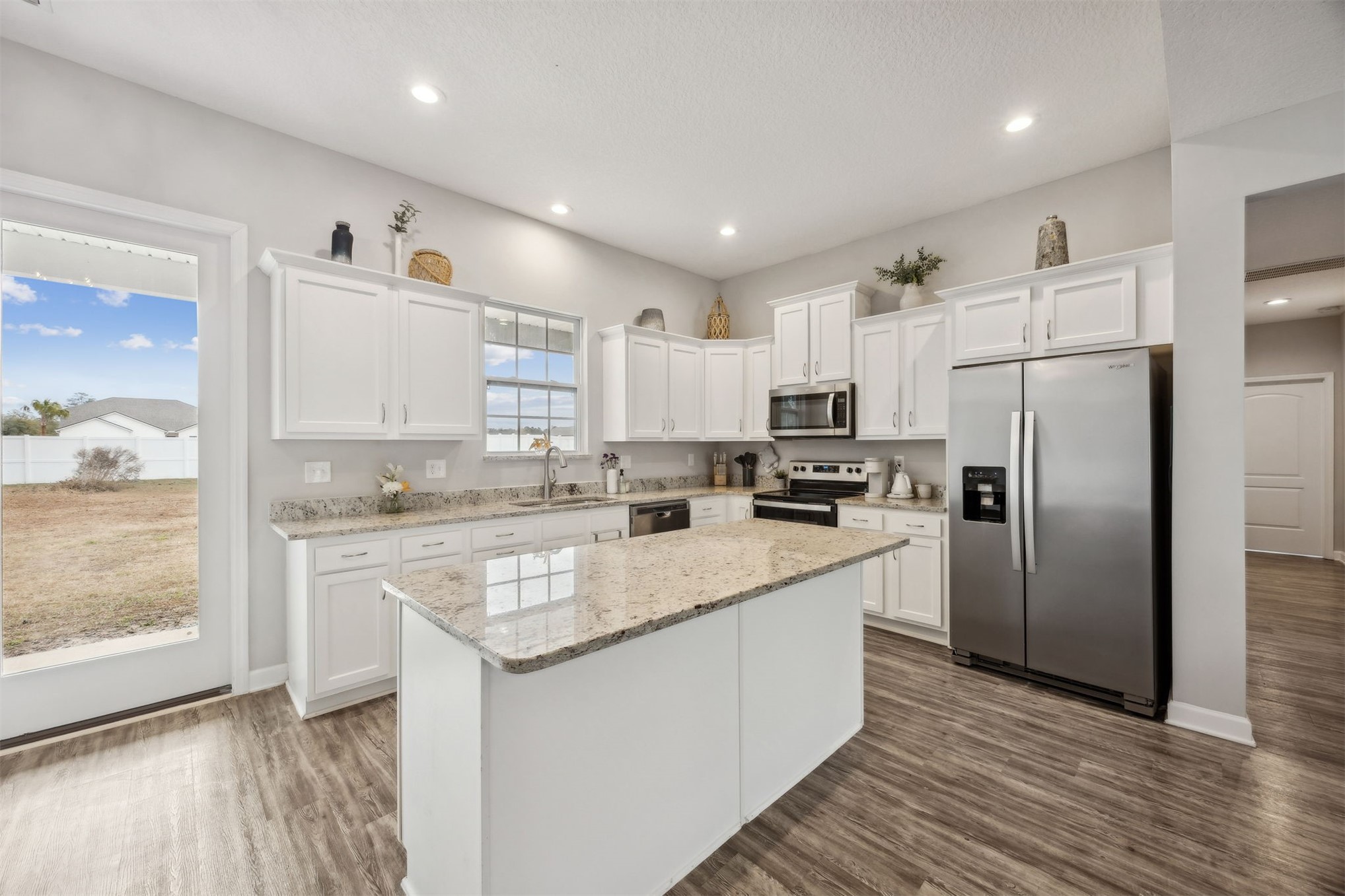 96718 Blackrock Road Yulee, FL 32097 - Photo 21 of 54 a kitchen with stainless steel appliances granite countertop a refrigerator a sink dishwasher a stove and white countertops with wooden floor