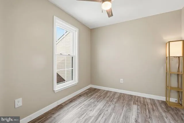 an empty room with a hardwood and ceiling fan
