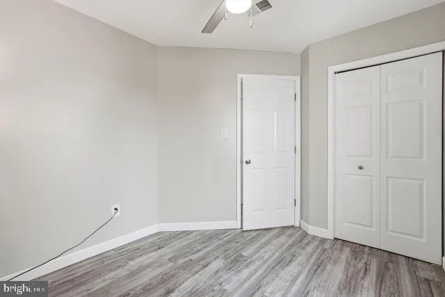 a view of an empty room and wooden floor cabinet and a ceiling fan