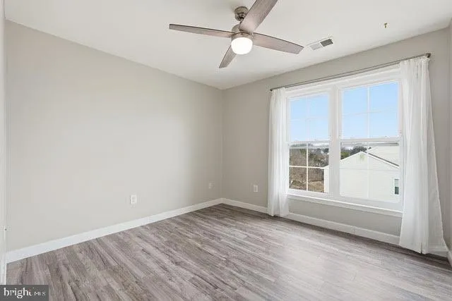 a view of empty room with wooden floor and fan