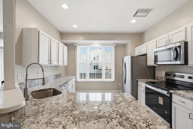 a kitchen with stainless steel appliances granite countertop a refrigerator a stove top oven a sink and dishwasher