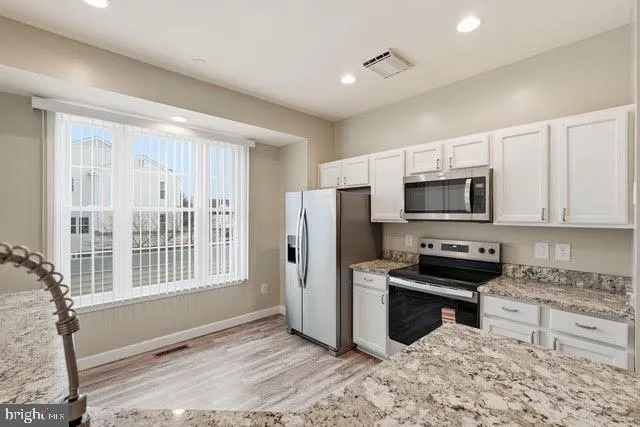 a kitchen with stainless steel appliances granite countertop a stove a sink and a refrigerator