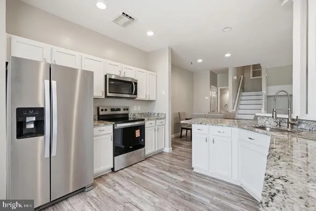 a large kitchen with stainless steel appliances granite countertop a stove refrigerator sink and dishwasher