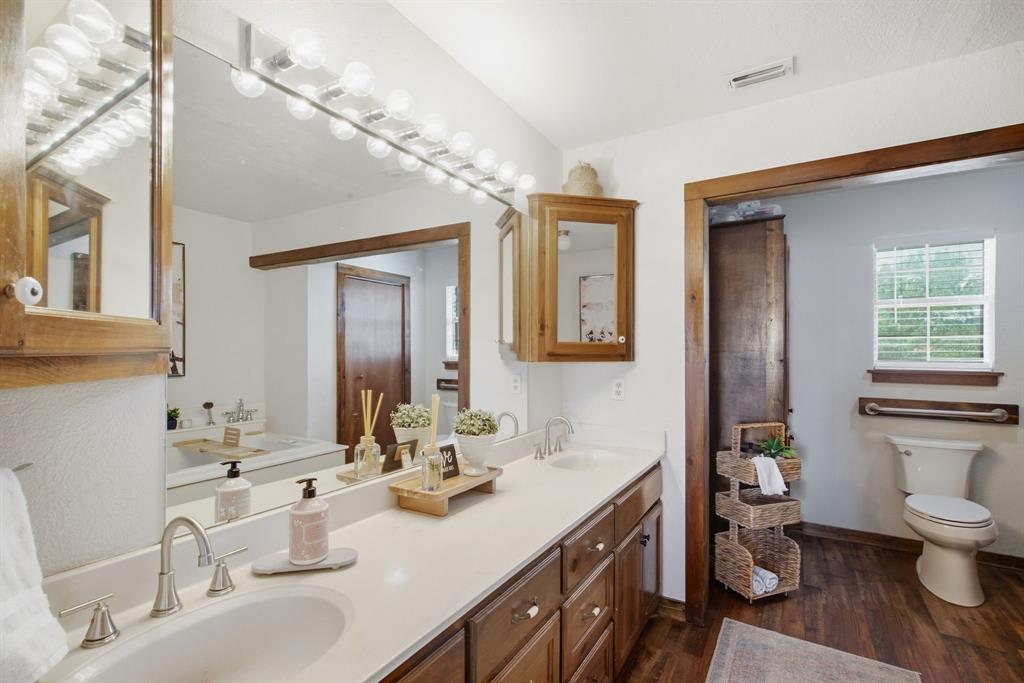 950 Johnson Bend Road Weatherford, TX 76088 - Photo 24 of 40 Spa-inspired primary bathroom featuring a dual-sink vanity with wood cabinetry, white quartz countertops, and polished nickel fixtures