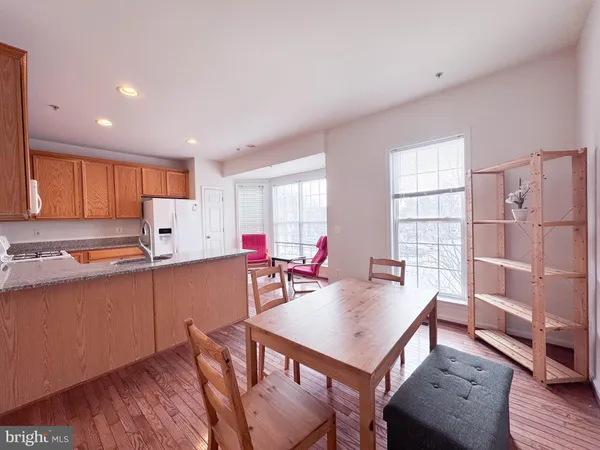 a kitchen with stainless steel appliances granite countertop a refrigerator a sink dishwasher a dining table and chairs with wooden floor