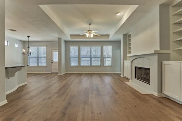 an empty room with chandelier fan and windows