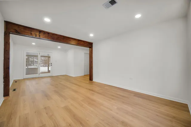 an empty room with wooden floor and windows