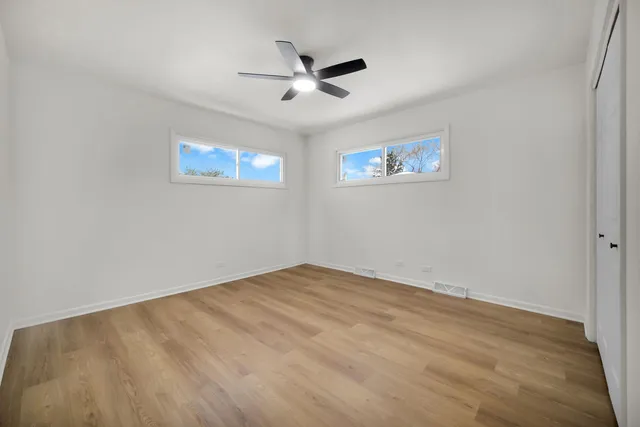 an empty room with wooden floor and ceiling fan