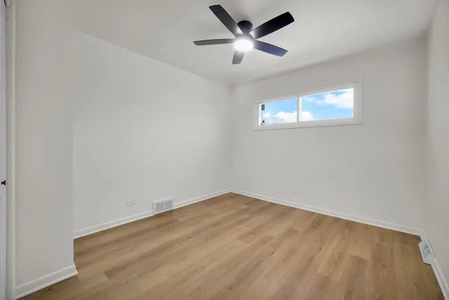 an empty room with a window and ceiling fan