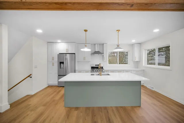 a large kitchen with stainless steel appliances kitchen island a large counter top and wooden floors
