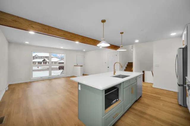 a large white kitchen with a sink a refrigerator and a stove top oven