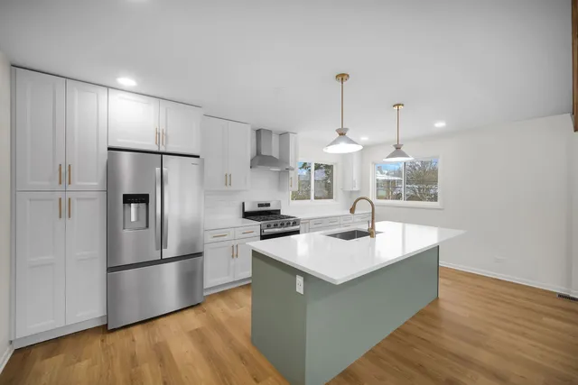 a kitchen with stainless steel appliances a sink a stove a refrigerator and island