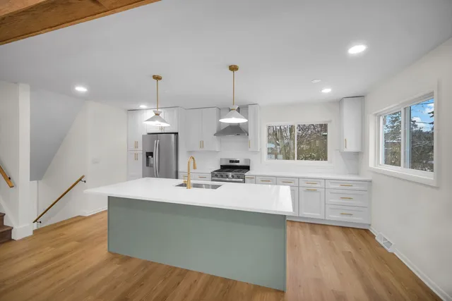 a large kitchen with kitchen island a stove a refrigerator a sink dishwasher and wooden cabinets with wooden floor