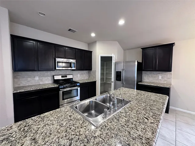 a kitchen with stainless steel appliances granite countertop a sink refrigerator and microwave