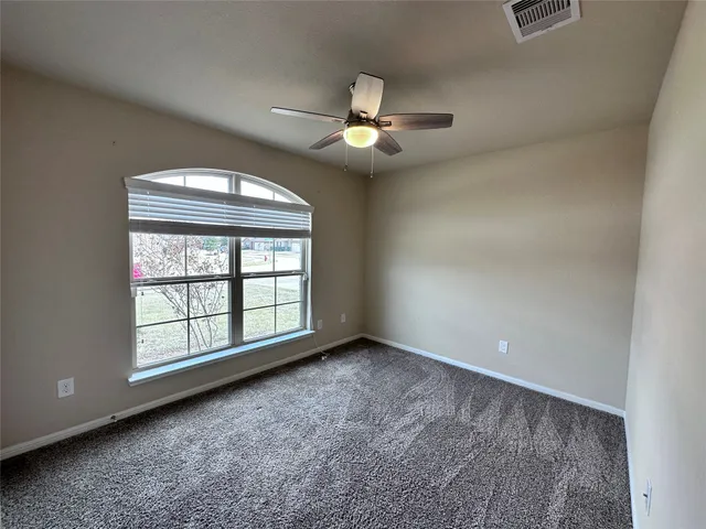 an empty room with chandelier fan and windows