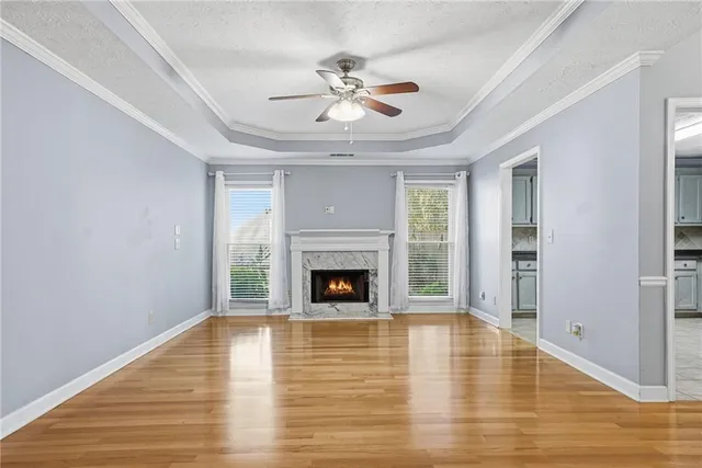 a view of a livingroom with a fireplace a ceiling fan and windows