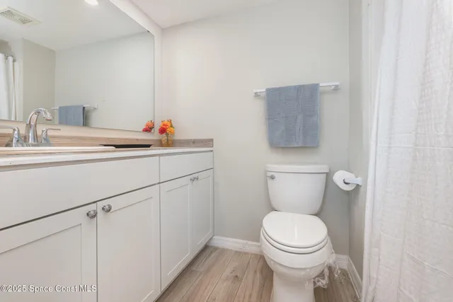 a bathroom with a toilet sink vanity and mirror