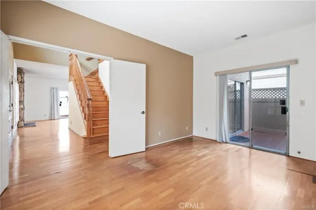 a view of an empty room with wooden floor and a bathroom