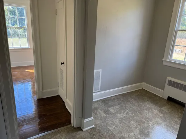 a view of hallway with window and wooden floor