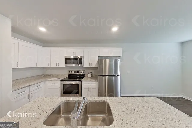 a kitchen with a sink a refrigerator and a stove top oven