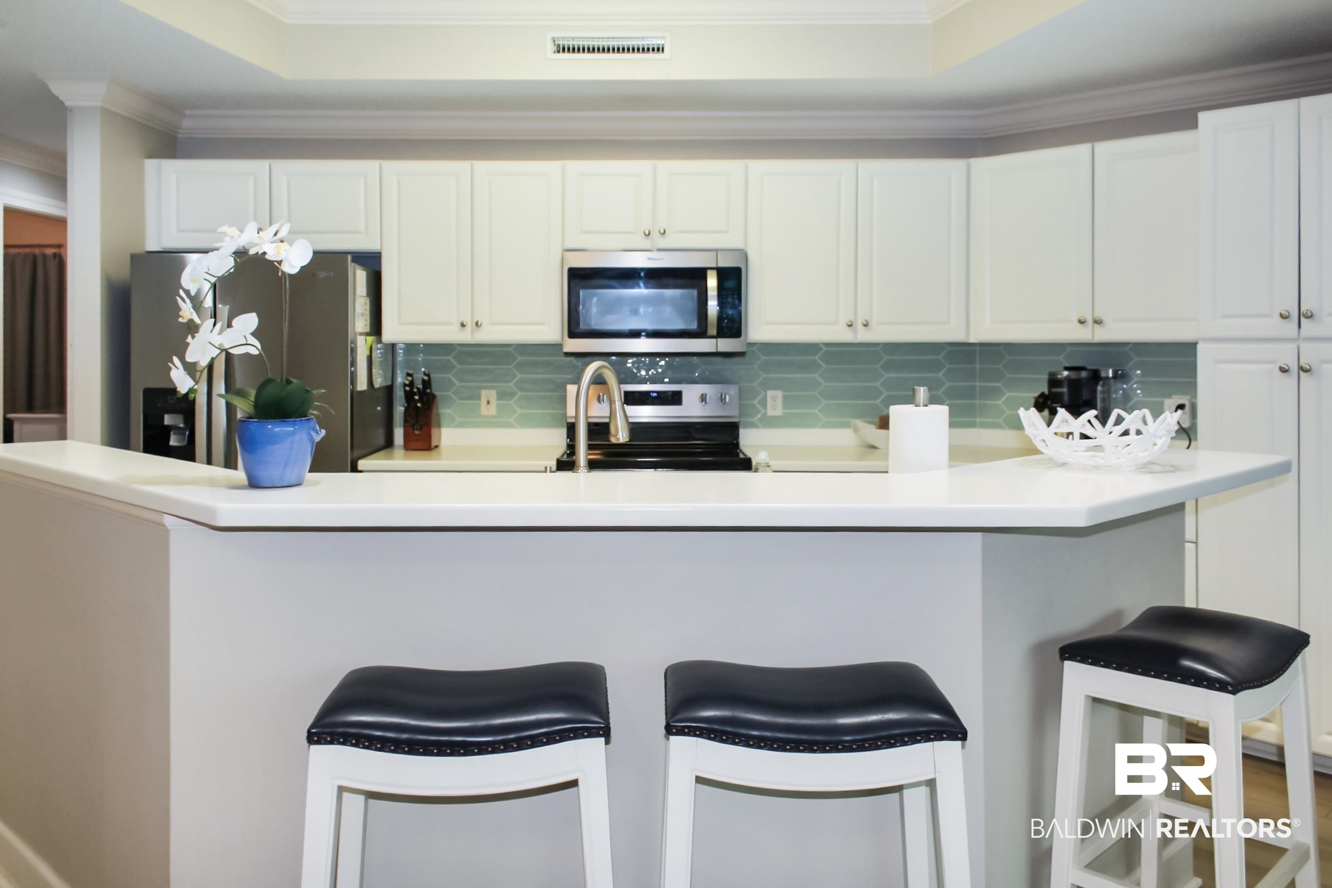 Kitchen featuring crown molding, appliances with stainless steel finishes, backsplash, white cabinetry, and a raised ceiling