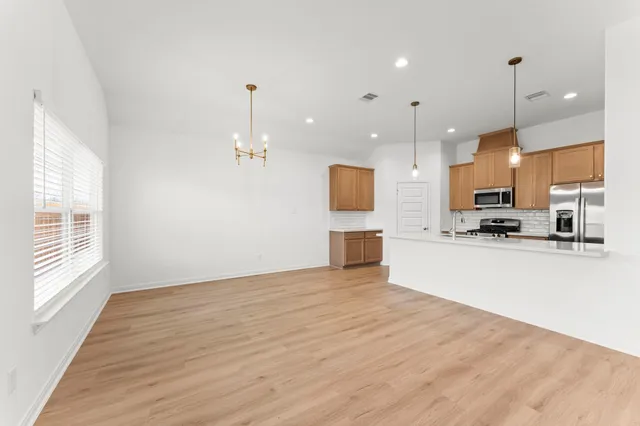 a view of kitchen with kitchen island wooden floor center island and stainless steel appliances