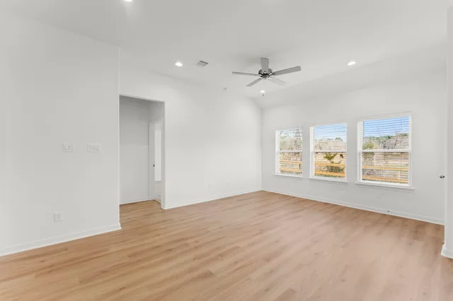 a view of an empty room with a window and wooden floor