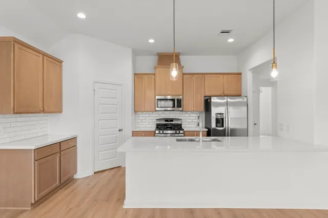 a kitchen with stainless steel appliances a refrigerator and a stove top oven