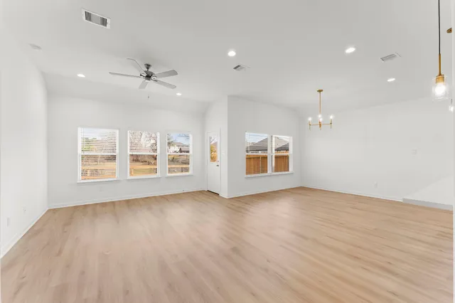 a view of an empty room with a window and wooden floor