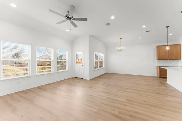 a view of an empty room with a window and a kitchen
