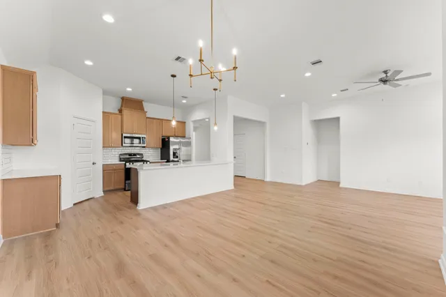 a view of kitchen with kitchen island stainless steel appliances sink cabinets and wooden floor