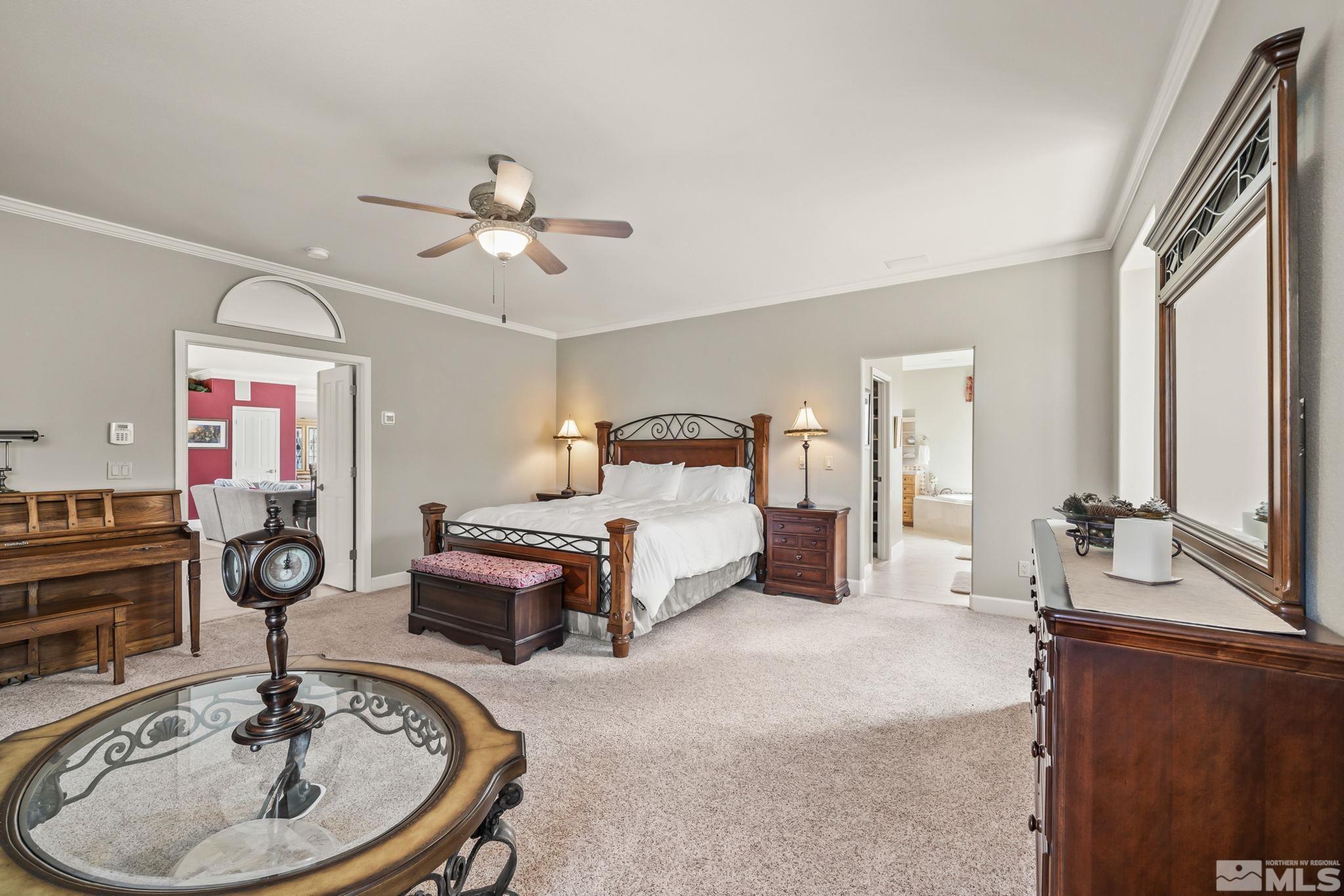 1335 Wolf Run Road Reno, NV 89511 - Photo 27 of 37 a spacious bedroom with a bed and a chandelier
