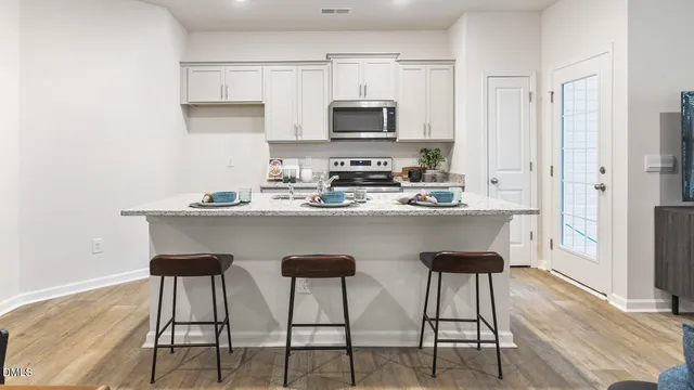 a kitchen with stainless steel appliances a dining table chairs microwave and sink