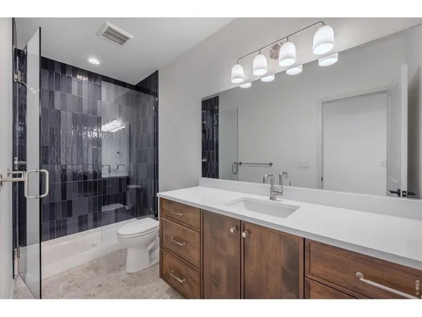 a bathroom with a sink a toilet a mirror and shower