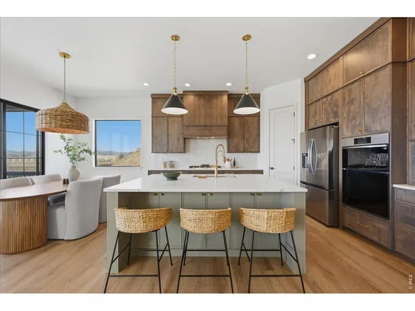 a kitchen with stainless steel appliances kitchen island granite countertop a table chairs and a refrigerator