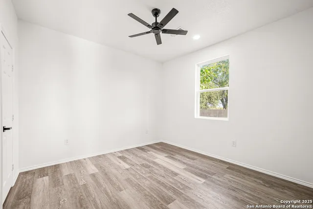 an empty room with a window and a ceiling fan