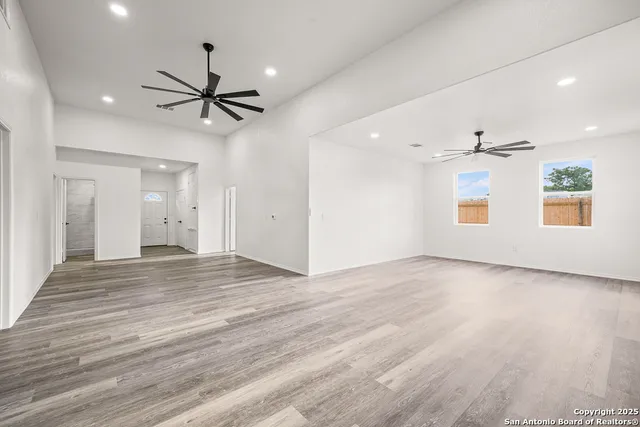 a view of an empty room with window and wooden floor