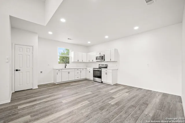a large white kitchen with wooden floors and white walls