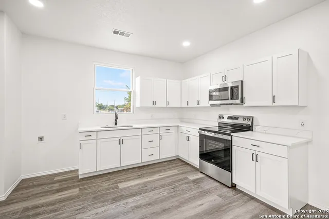 a kitchen with granite countertop white cabinets white stainless steel appliances with a sink and dishwasher