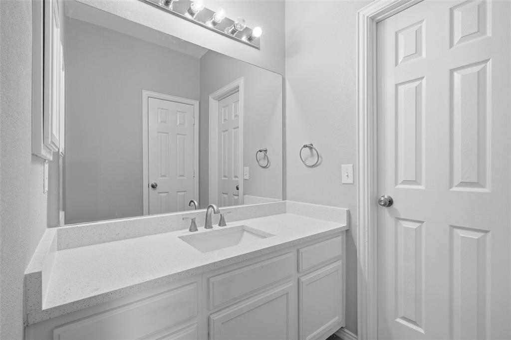 3903 Rive Lane Addison, TX 75001 - Photo 25 of 40 Jack and Jill bathroom with updated with a white quartz countertop, undermount sink, brushed nickel fixtures, and a large vanity mirror with Hollywood-style lighting — this secondary bathroom punches above its weight. Clean, bright, and move-in ready.
