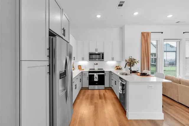 a kitchen with stainless steel appliances granite countertop a refrigerator sink and white cabinets