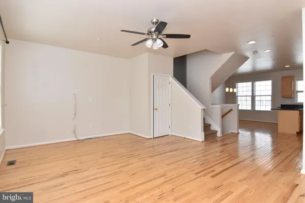 a view of an empty room with wooden floor and a ceiling fan