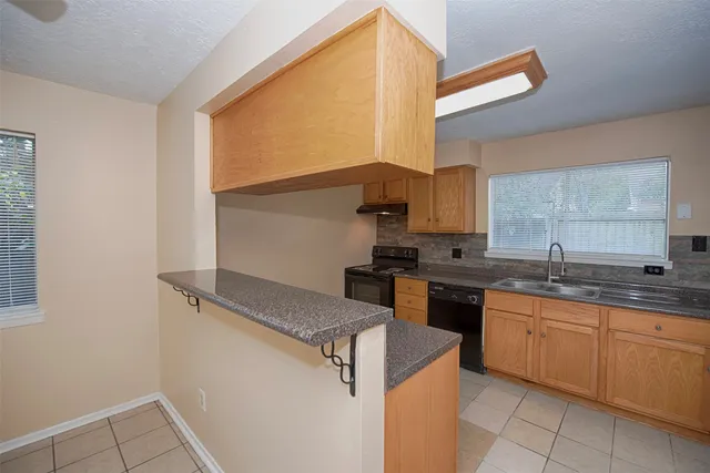 a kitchen with granite countertop a sink a stove and cabinets