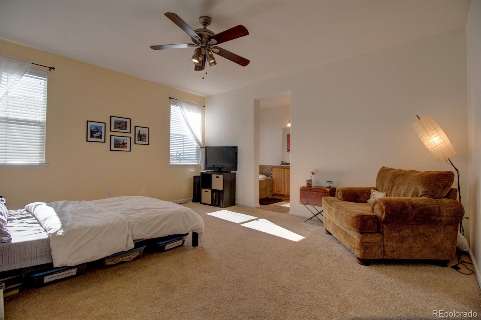 3491 Cascina Place, Unit D Highlands Ranch, CO 80126 - Photo 14 of 22 a spacious bedroom with a bed a couch and a chandelier