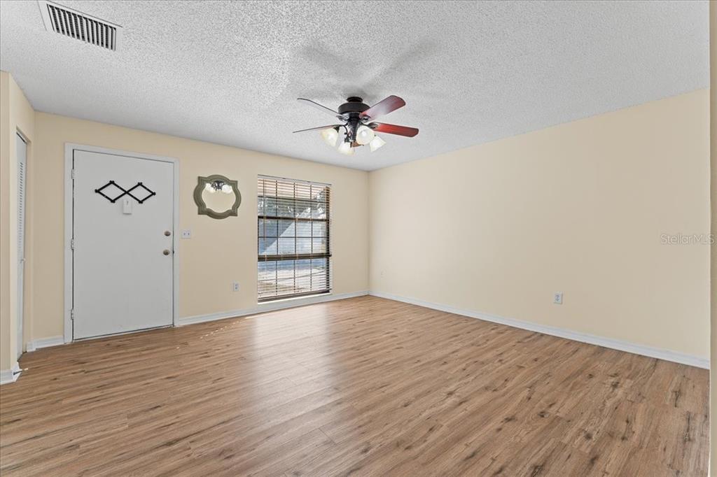 3701 Modesto Street New Port Richey, FL 34655 - Photo 6 of 41 an empty room with wooden floor chandelier fan and windows