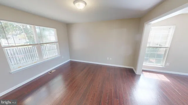 a view of a kitchen and an empty room with wooden floor and a window