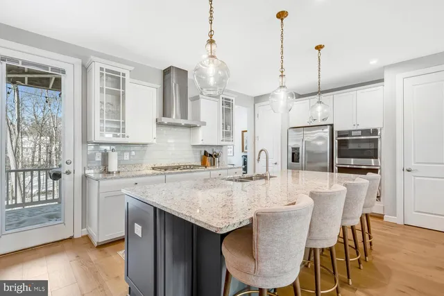 a kitchen with stainless steel appliances a dining table chairs and wooden floor
