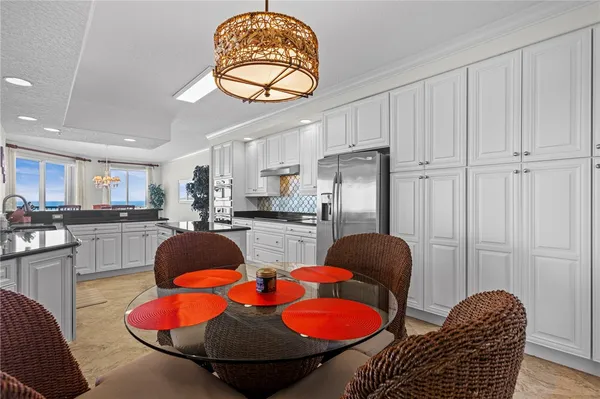 a kitchen with stainless steel appliances granite countertop a stove a refrigerator and a dining table with wooden floor