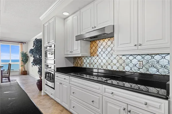 a kitchen with granite countertop white cabinets and stainless steel appliances